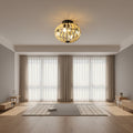 A ceiling-mounted light fixture with a black metal frame and many small cream-colored bead-like spheres, shown lit in a real interior room with curtains, wall sconce, and a floor lamp.
